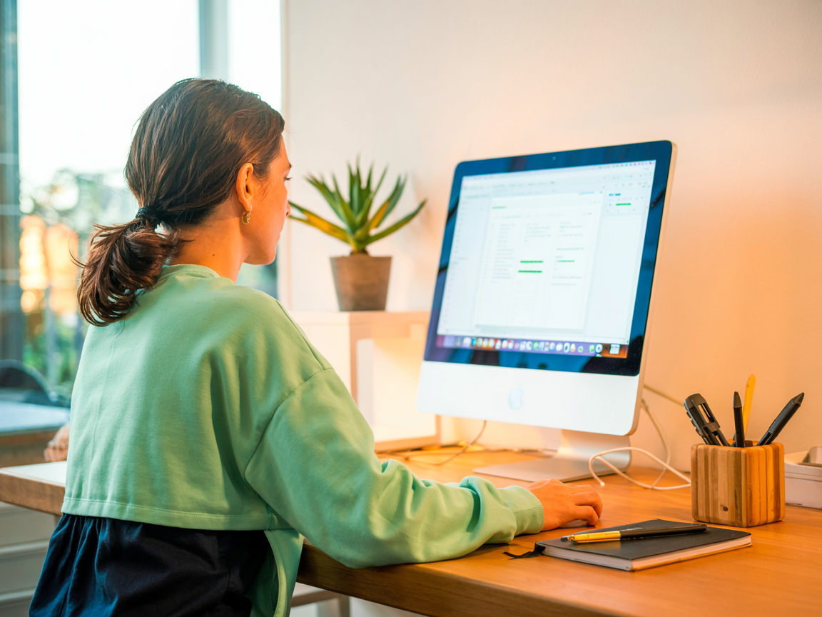 Frau arbeitet produktiv am Computer und symbolisiert digitale Teilhabe und berufliche Aktivitaet im Alter. Illustration fuer Kompetenz und Unabhaengigkeit. Konzept fuer flexible AHV-Rentner bei Ausgleichskasse Migros.